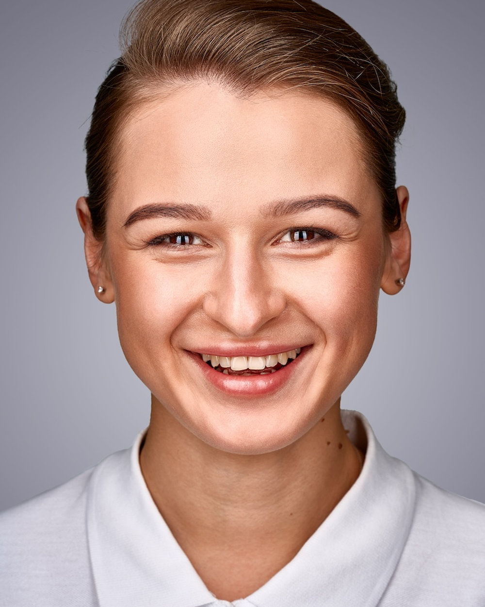 Studio business headshot of a smiling woman against a soft grey background
